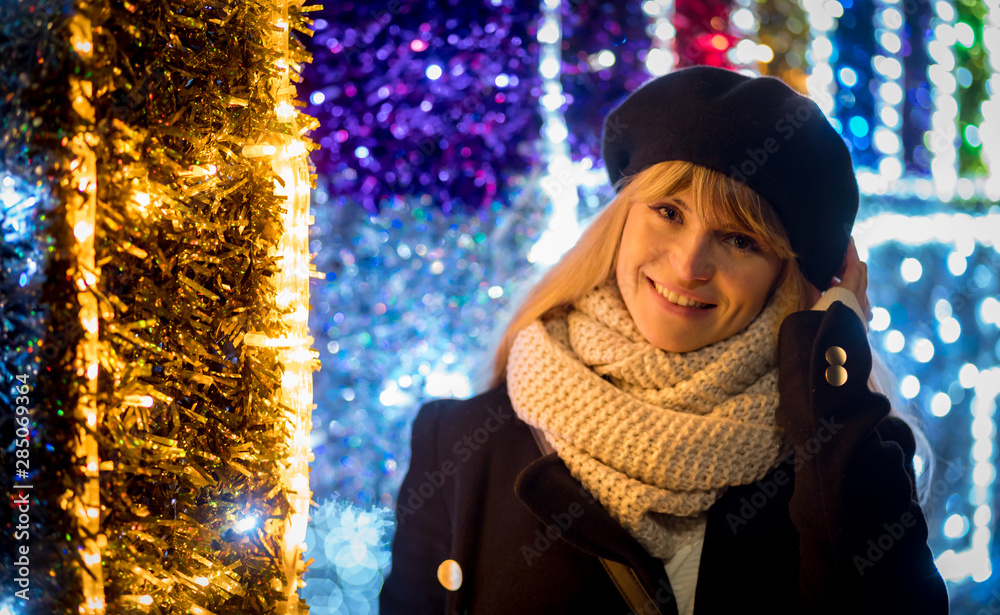 圣诞节期间，快乐微笑的女孩走在明亮的小巷里