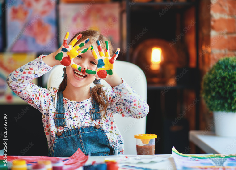 有趣的小女孩笑着画出手被油漆弄脏了。