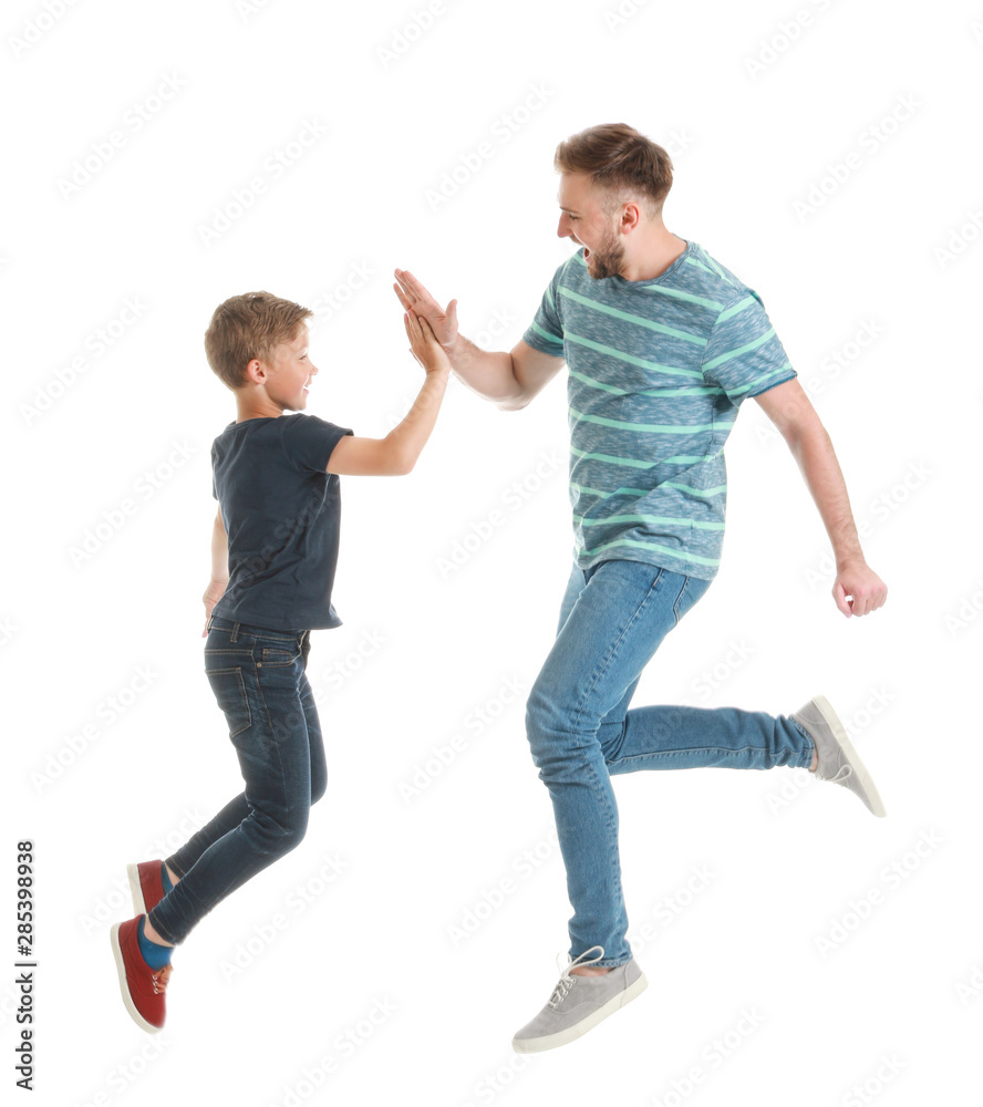 Jumping father and son giving each other high-five on white background