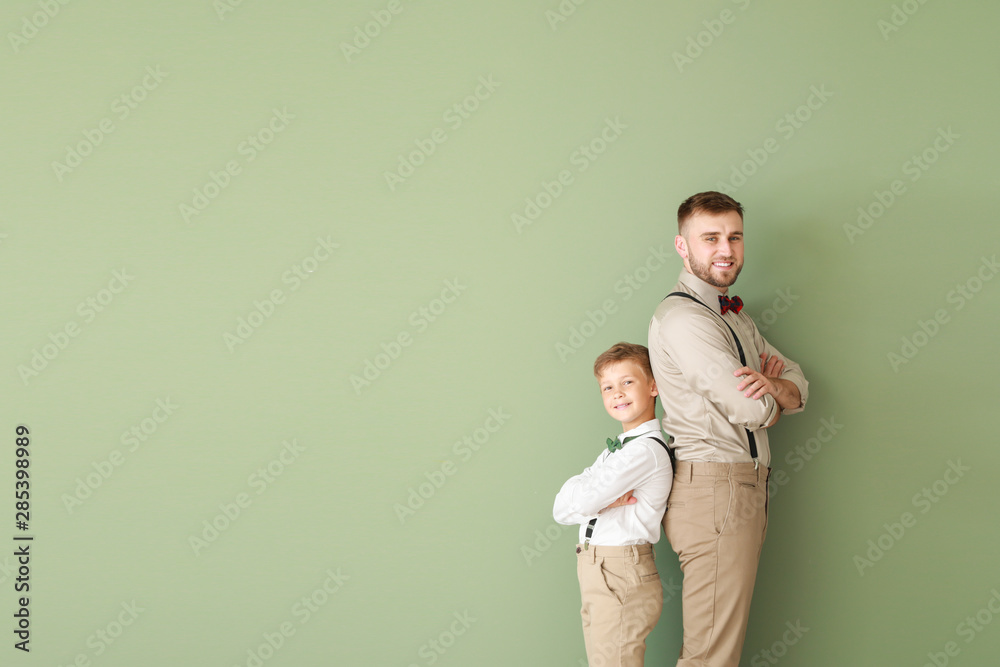 Portrait of fashionable father and son on color background