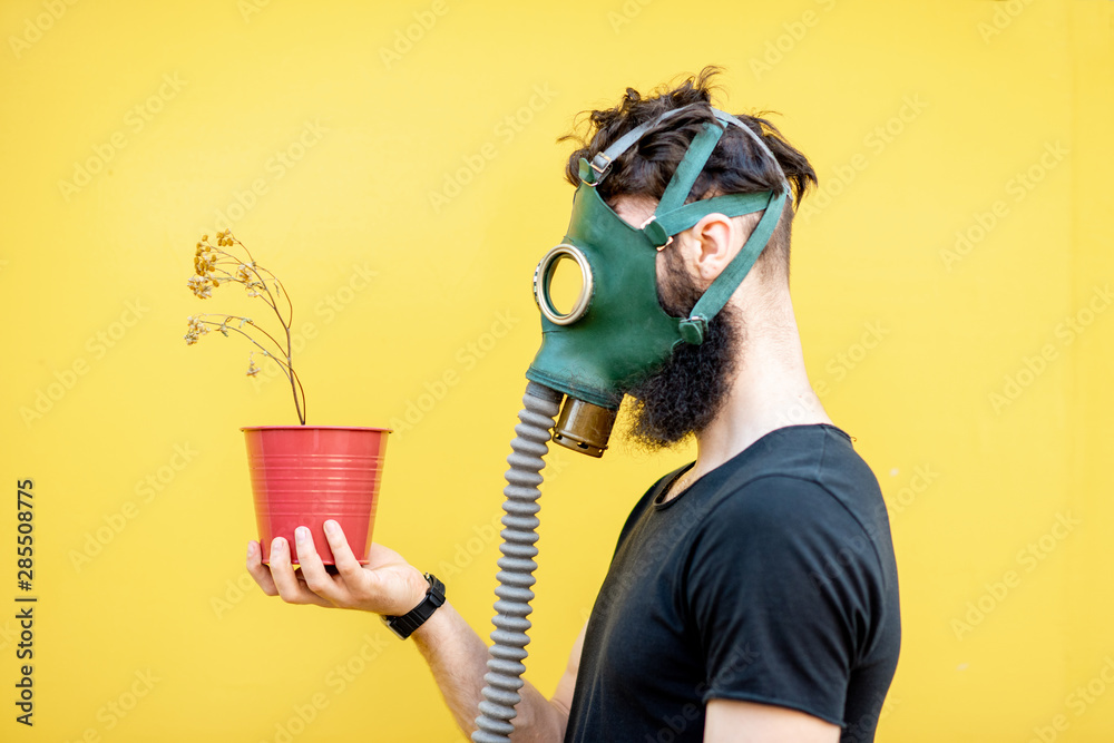 一个悲伤的男人的画像，黄色背景上戴着防毒面具和干花盆。可怜的ec的概念