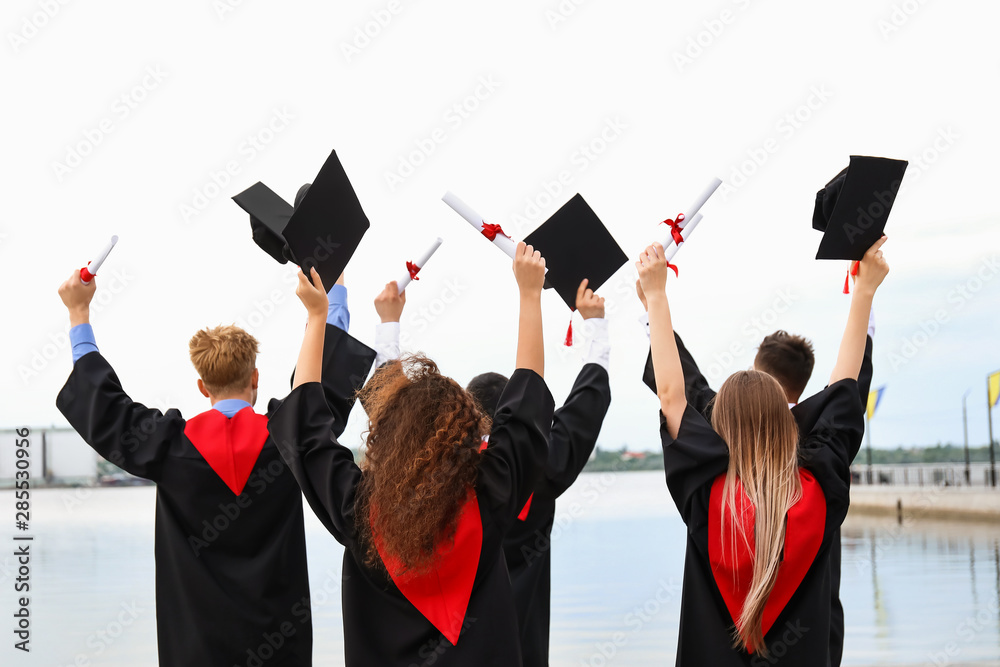 快乐的学生，毕业那天穿着学士长袍在户外