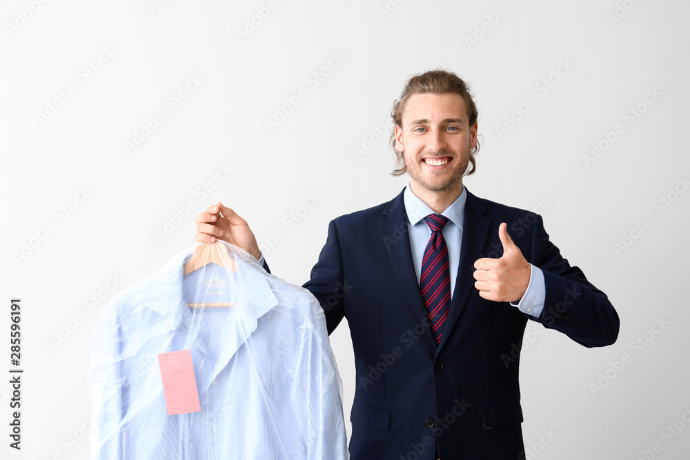 干洗后穿着衣服的商人在白色背景上竖起大拇指