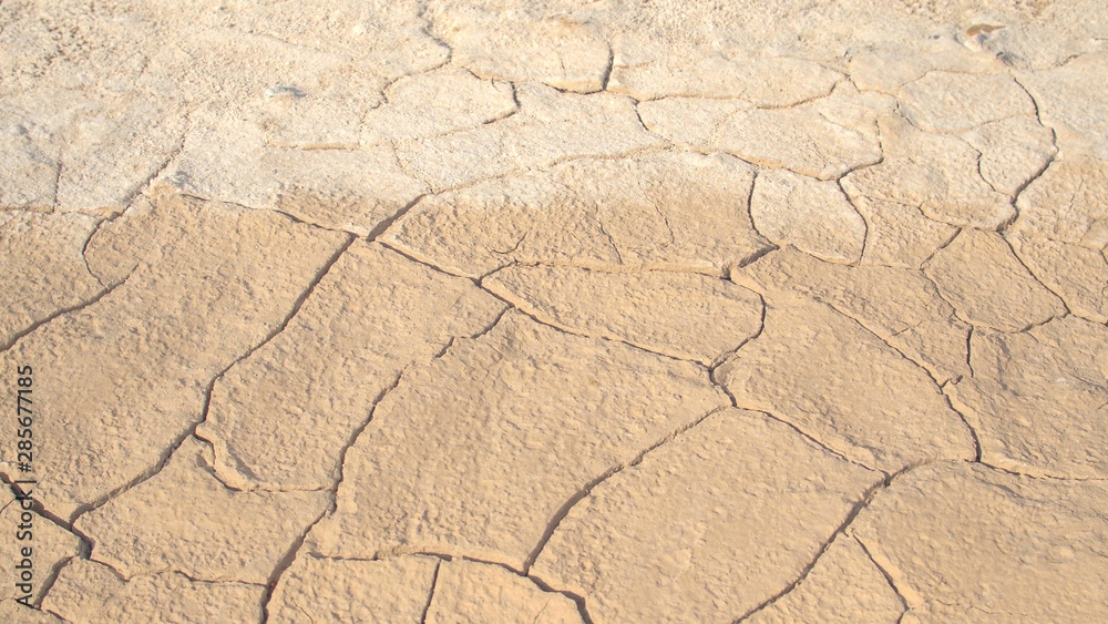 特写：炎热阳光充足的沙漠中干燥开裂的干旱土壤的细节