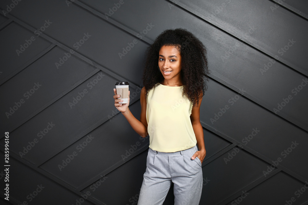 Portrait of beautiful African-American woman with cup of coffee on dark background
