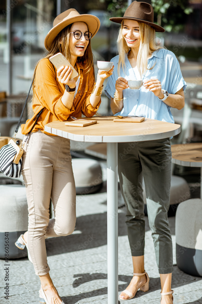 两位女性最好的朋友在咖啡馆露台上共度时光，和咖啡一起站在一起感觉很开心