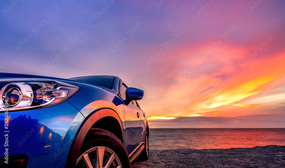 日落时停在海滩边的运动时尚设计的蓝色紧凑型SUV。混合动力和电动汽车
