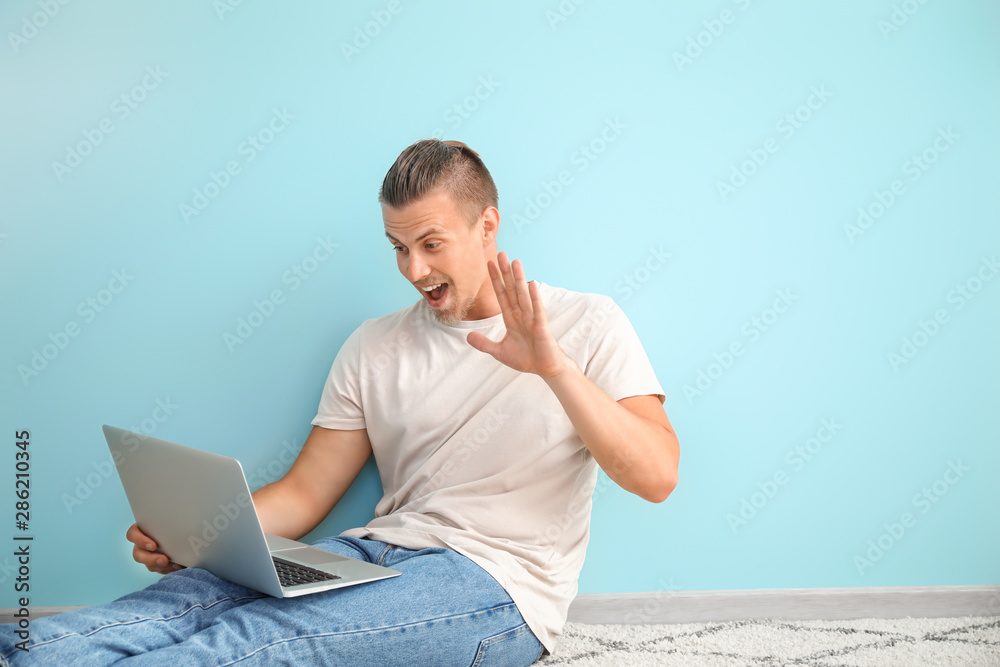 男博主拿着笔记本电脑坐在彩色墙上