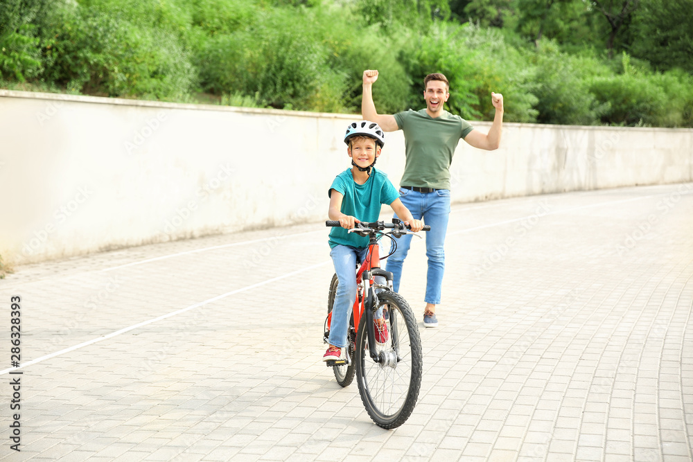 父亲为儿子在户外学会骑自行车感到骄傲