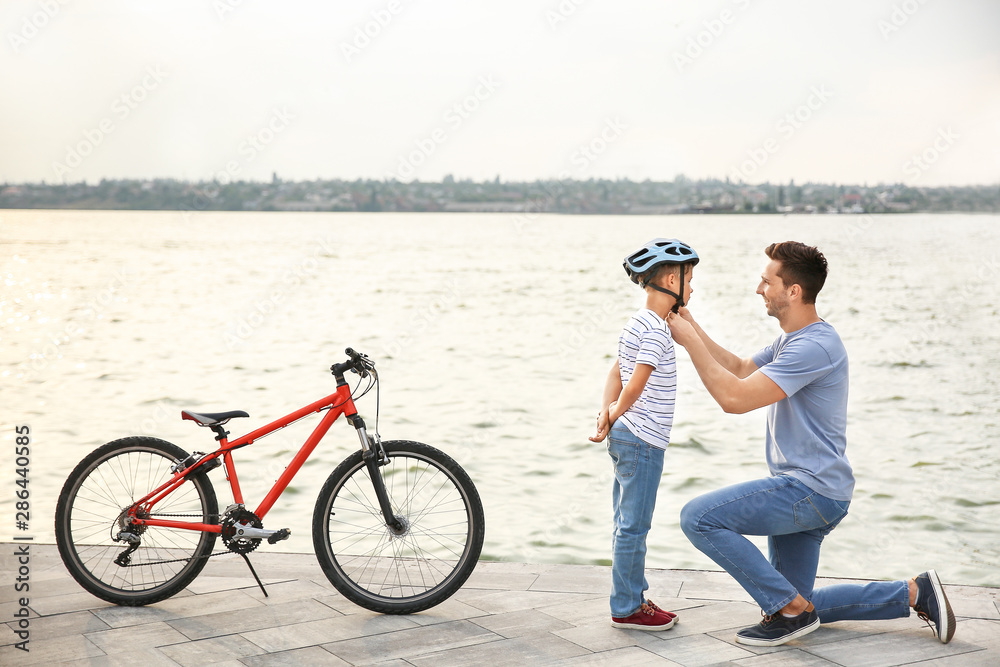 父亲在户外骑自行车前帮儿子戴上头盔