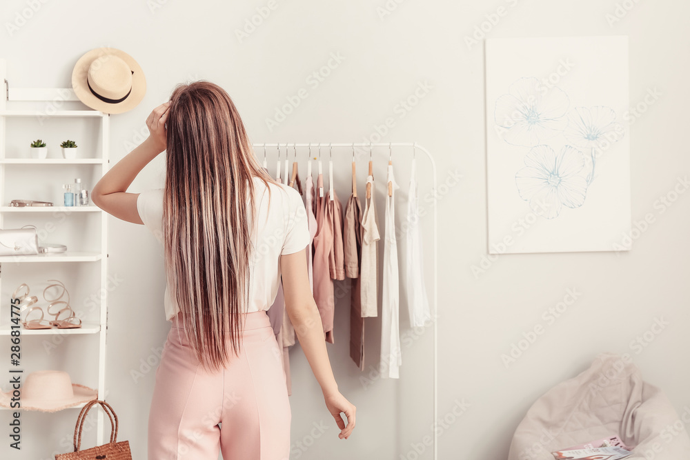 年轻女子在更衣室选衣服，后视图