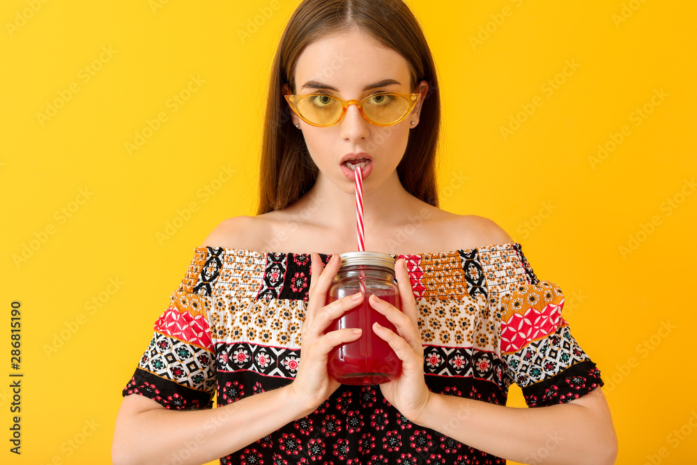 年轻女性在彩色背景下饮用健康果汁