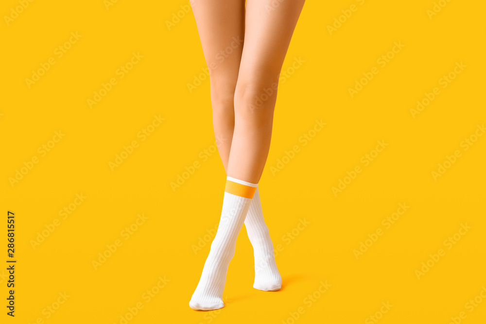 Legs of young woman in socks on color background