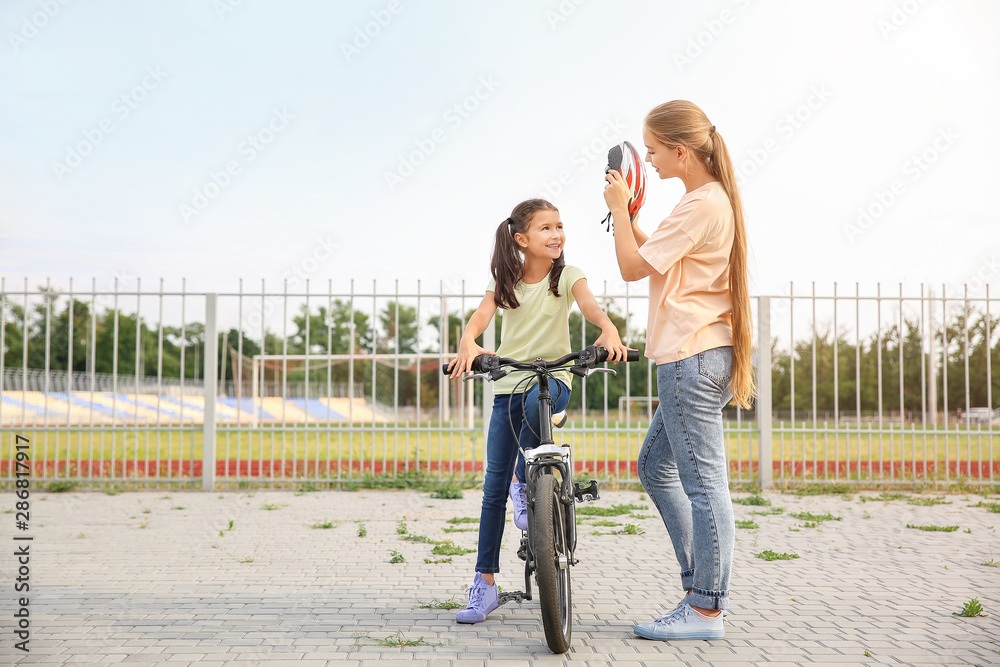 母亲在户外帮助女儿戴上自行车头盔
