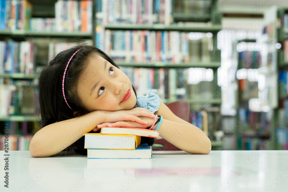 亚洲小女孩坐在学校图书馆里，抬头思考未来，教育学习kno