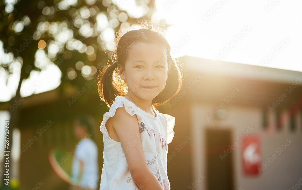 日落时公园里有酒窝的亚洲小女孩的户外肖像