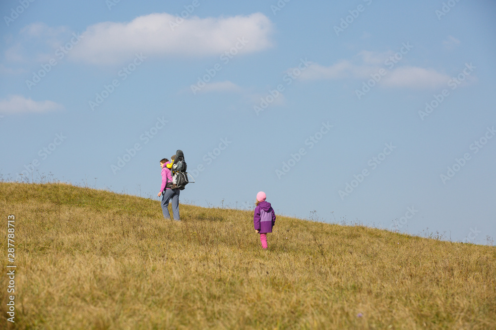 Mother with children hiking on a nice autumn day carrying kid