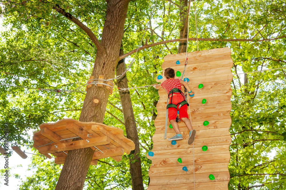 快乐的孩子在公园的木墙上攀岩