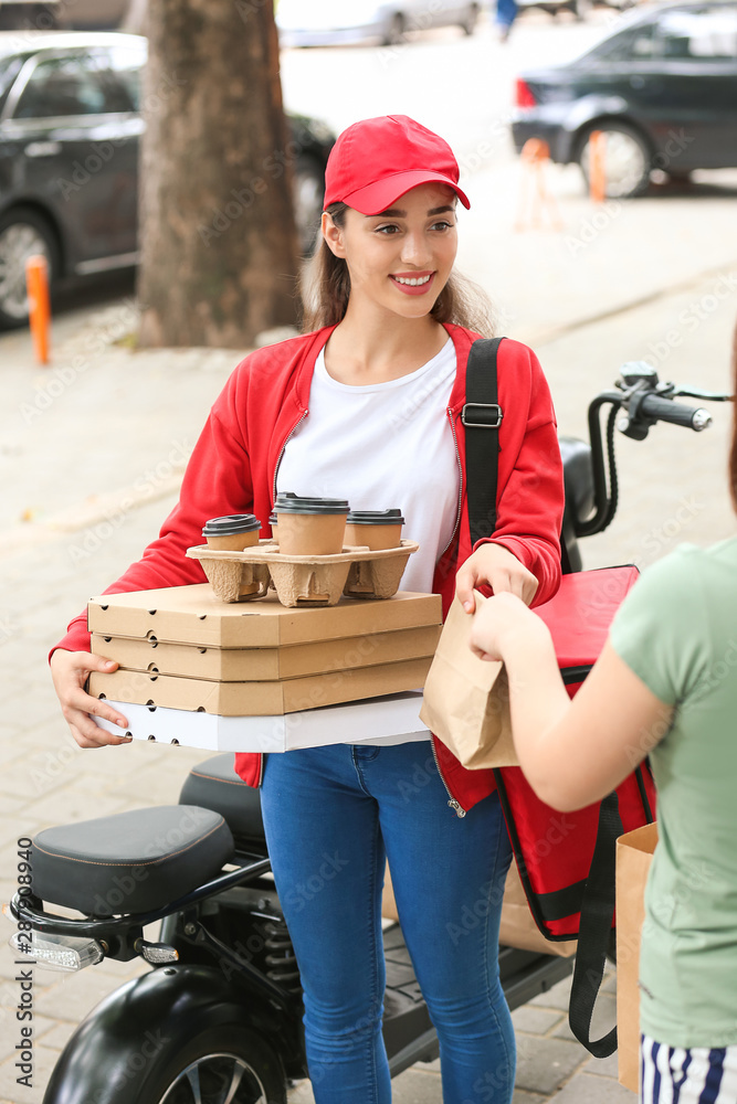 Woman taking order from courier of food delivery service outdoors