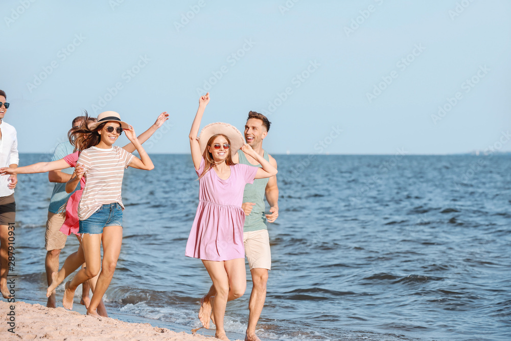 快乐的朋友在度假胜地的海滩上跑步