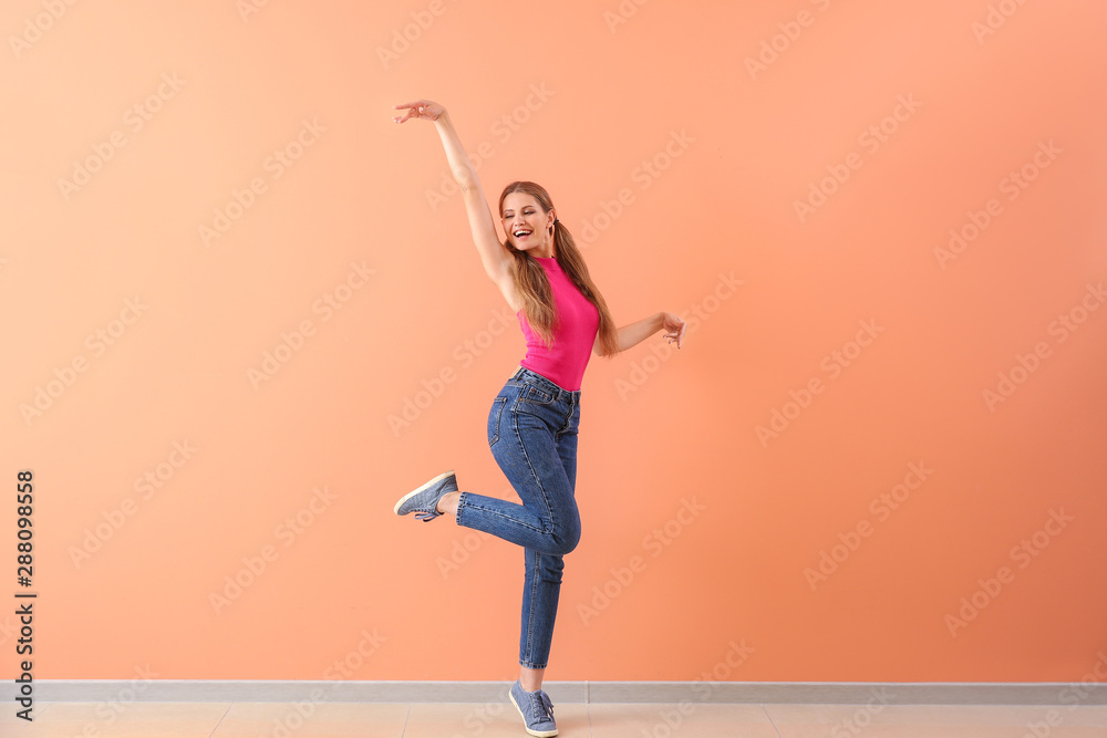 美丽的年轻女子在彩色墙上跳舞
