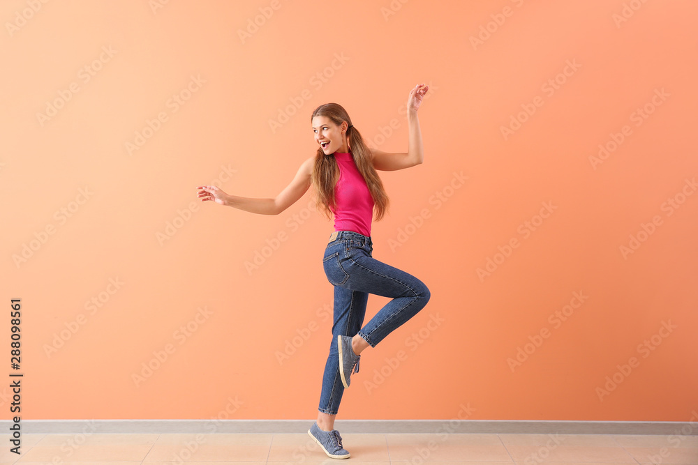 美丽的年轻女子在彩色墙上跳舞