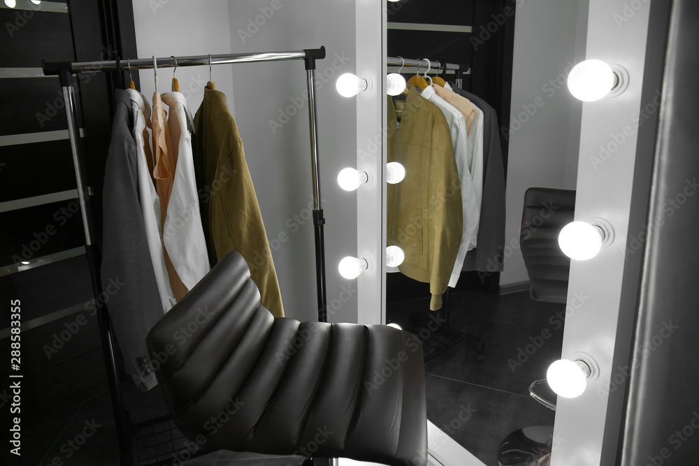 现代更衣室里有衣服、椅子和时尚镜子的架子
