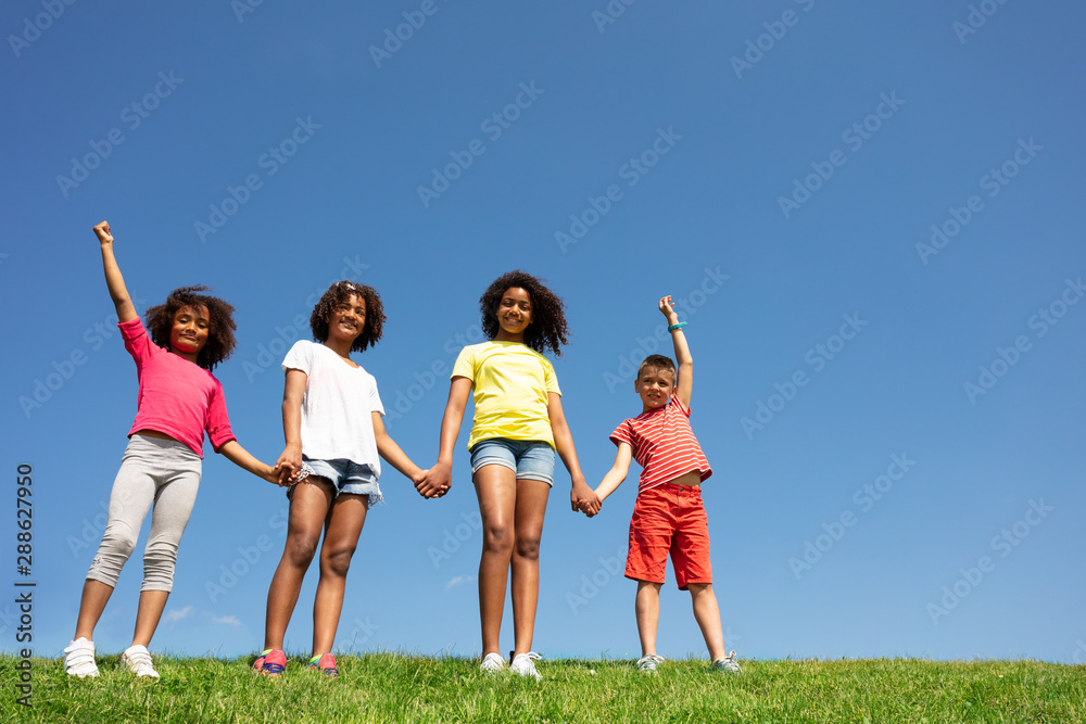 Group of kids stand holding hand over clean sky