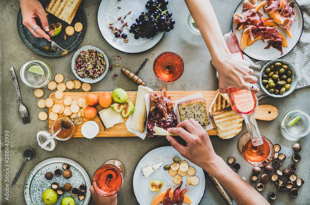 Mid-summer picnic with wine and snacks. Flat-lay of charcuterie and cheese board, rose wine, nuts, o