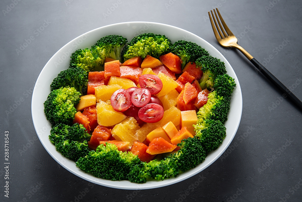 A plate of nutritious delicious fruit and vegetable salad on a black background
