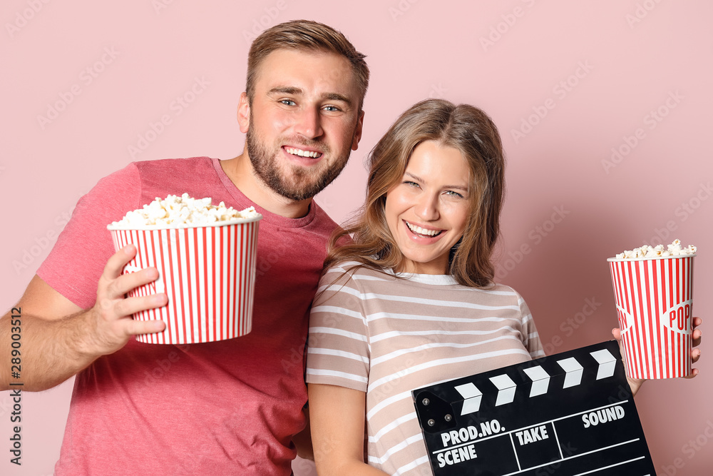 彩色背景下爆米花和电影拍手的年轻夫妇