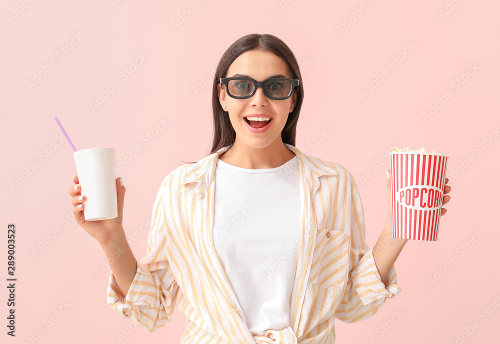 拿着爆米花和饮料的年轻女子在彩色背景下看电影