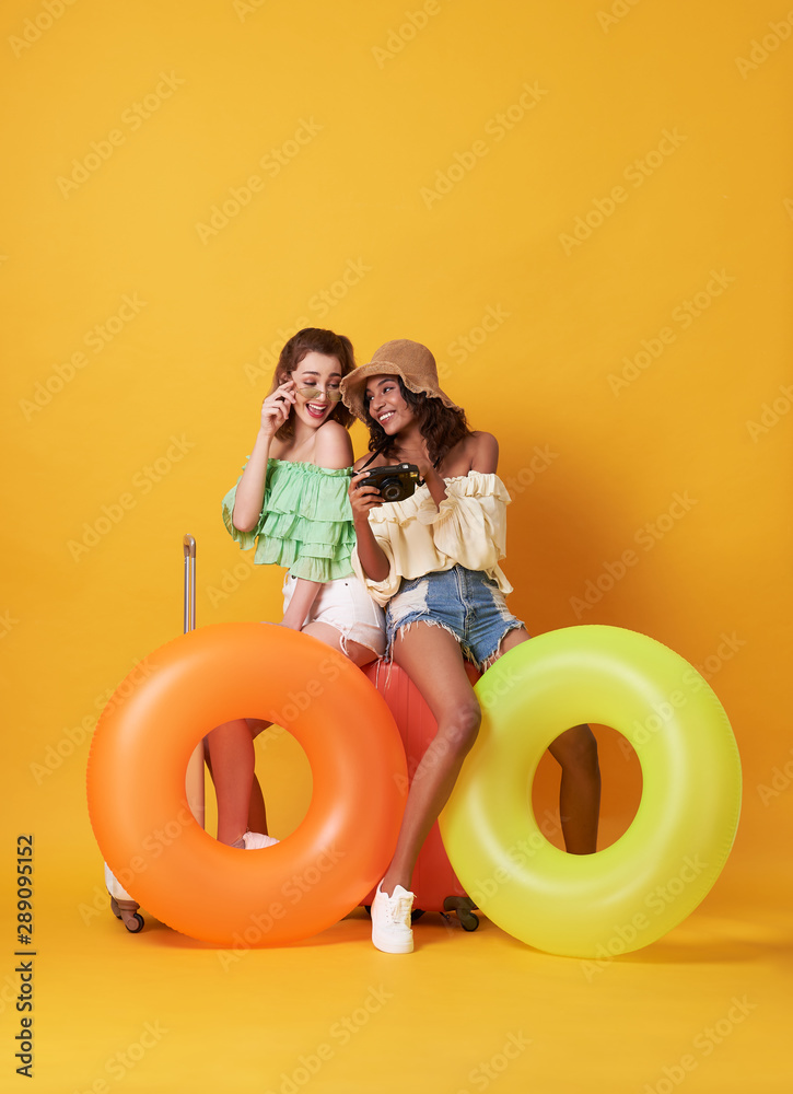 快乐的朋友女人穿着夏装坐在行李箱上，橡胶圈被隔离