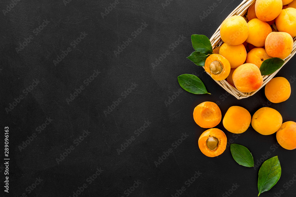 篮子里的新鲜生杏子，黑色背景，带叶子的文本图案俯视空间