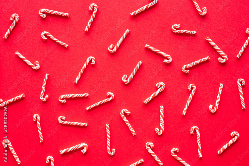 红色背景的糖果手杖，用于圣诞和新年快乐概念。平面俯视图。