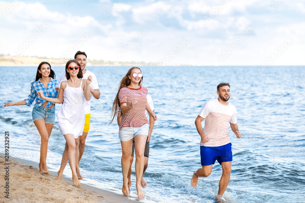 快乐的朋友们在度假胜地的沙滩上跑步