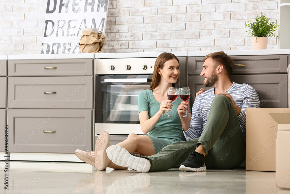 Happy young couple drinking wine after moving into new house