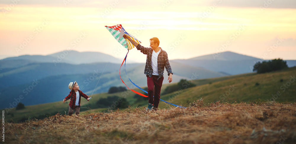 幸福家庭的父亲和孩子在草地上放风筝。