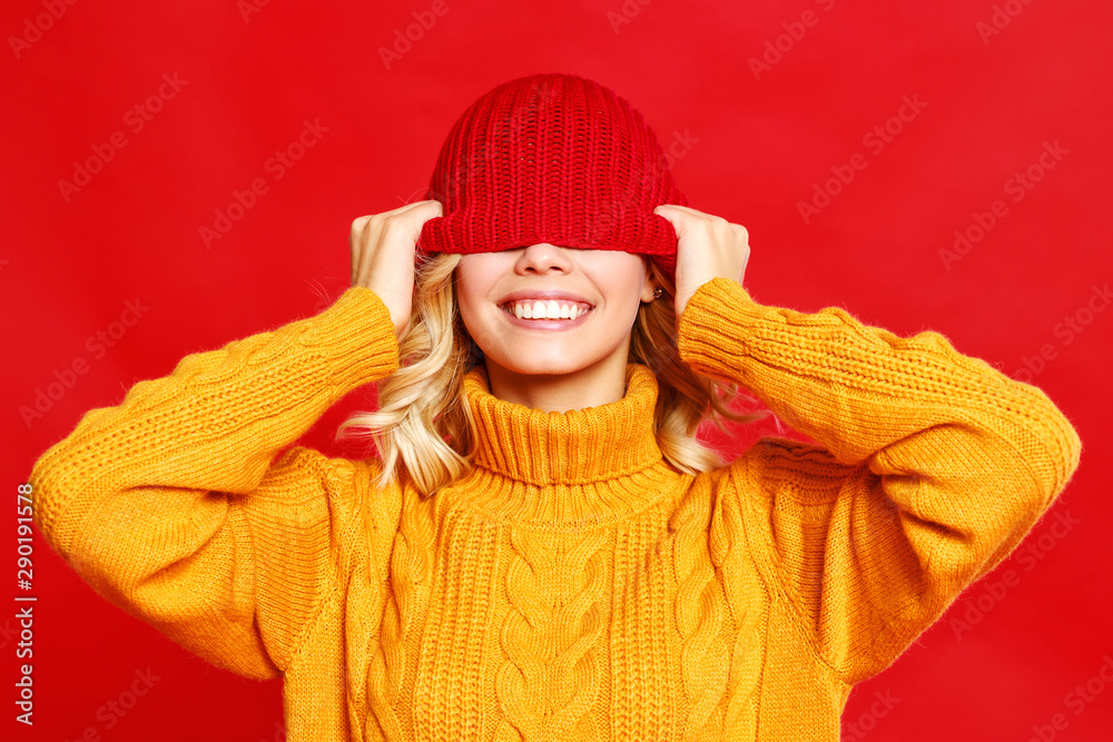 快乐、感性、开朗的女孩，带着红色背景的针织秋帽大笑。