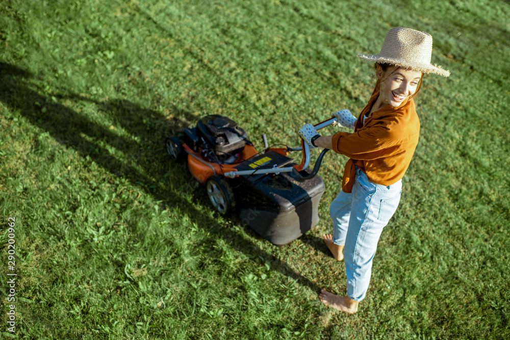 一位穿着休闲的年轻美女的画像，她开着割草机割草。