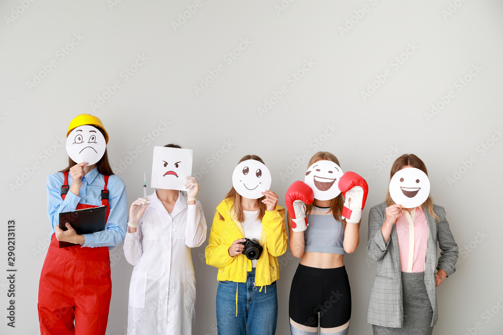 一群女工在浅色背景下用画好的表情符号遮住脸