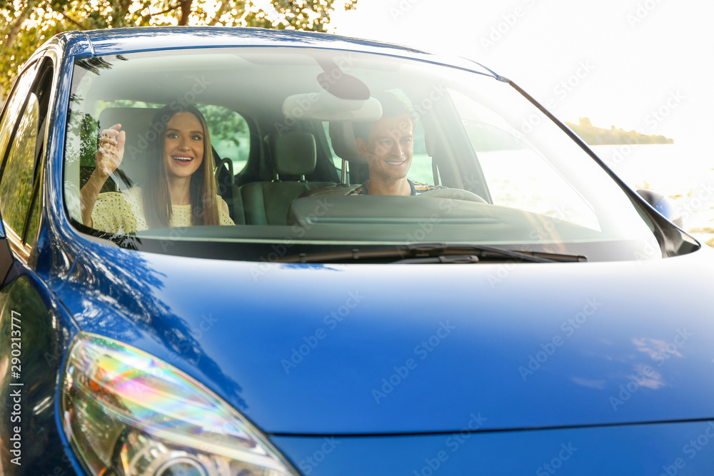 幸福的一对夫妇坐在他们的新车里，从挡风玻璃窗户看