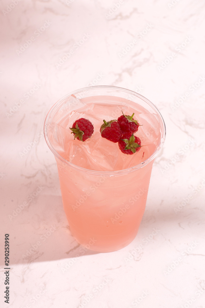淡背景玻璃杯中的新鲜树莓夏日果汁