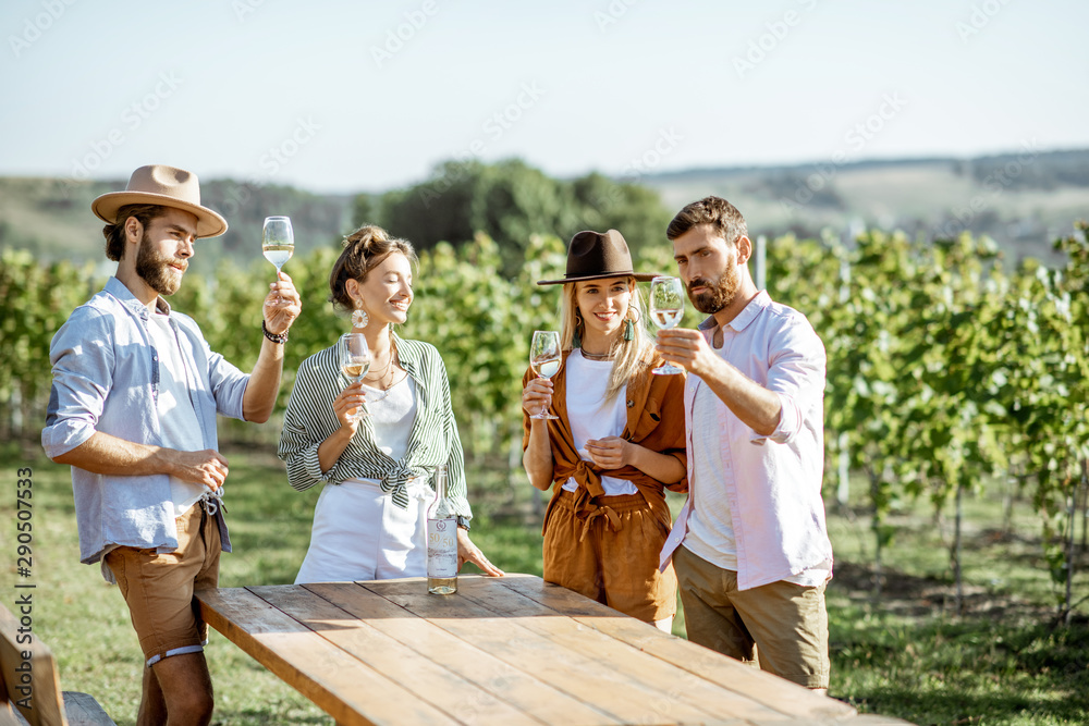 一群穿着休闲的年轻朋友在一起玩得很开心，在阳光明媚的葡萄园里品尝葡萄酒