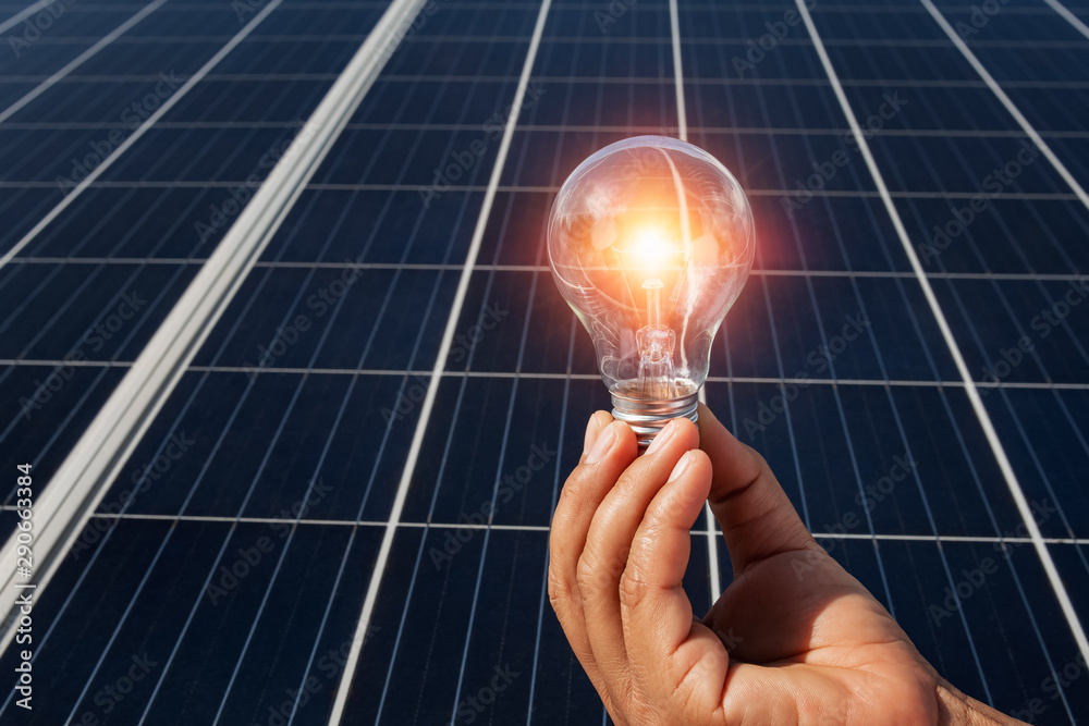 太阳能电池板上的手持灯泡概念——自然界中的清洁能源