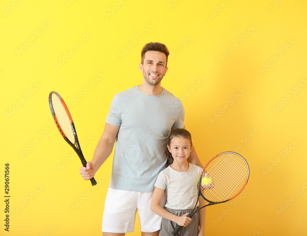 小女孩和她的父亲在彩色背景上拿着网球拍