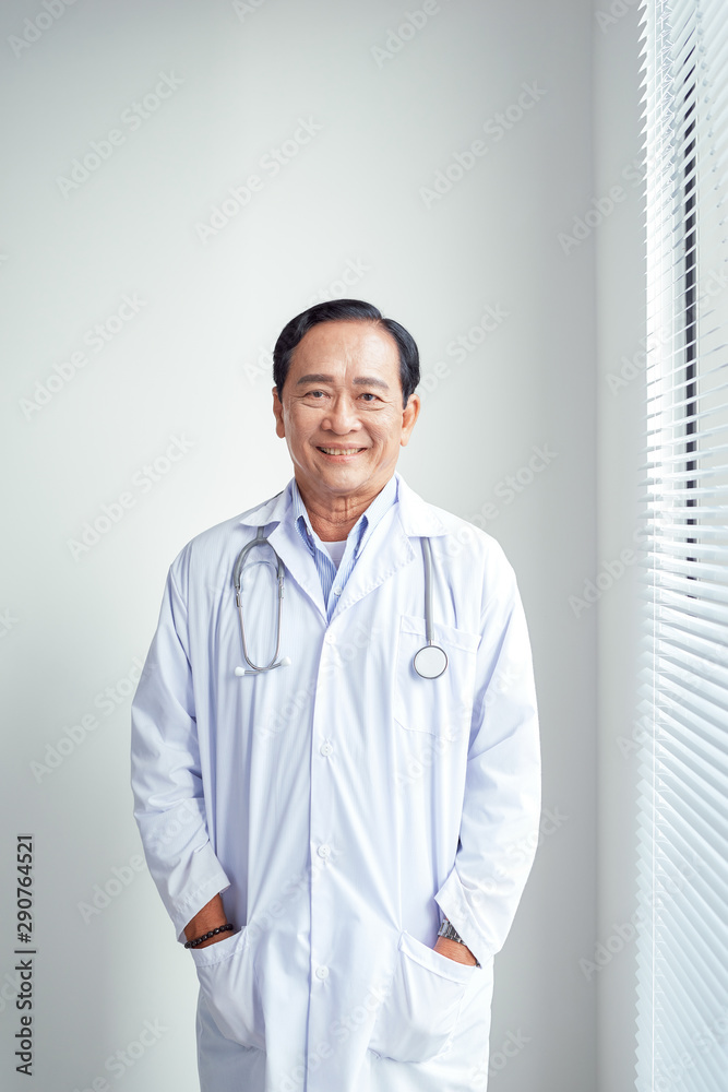 亚洲医生穿着白大褂站在医院里看着镜头的肖像