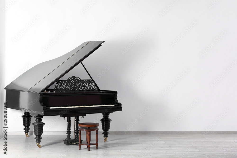 Black grand piano near white wall in empty room