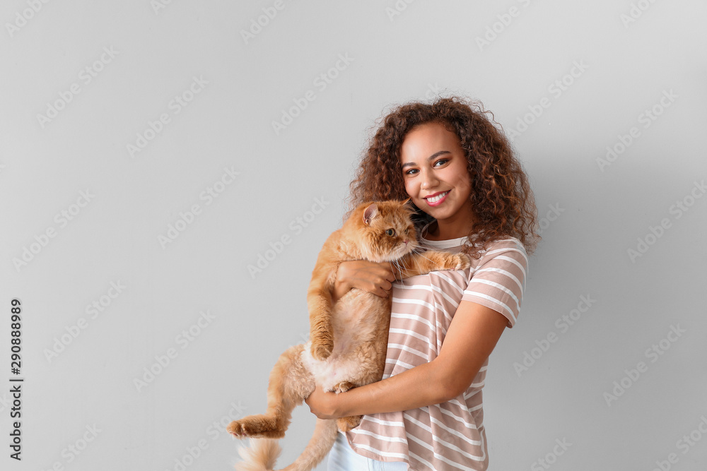 年轻的非裔美国女性，浅色背景下有一只可爱的猫