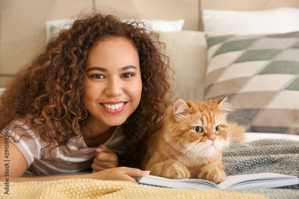 年轻的非裔美国妇女带着可爱的猫在家看书